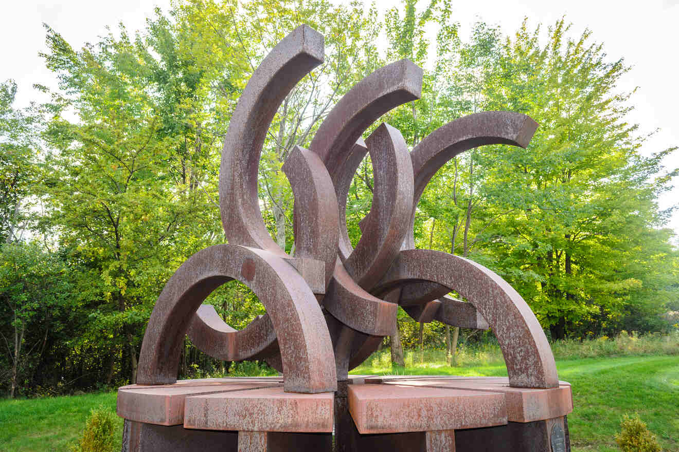 A large abstract metal sculpture in a park setting, representing modern art in a natural environment.
